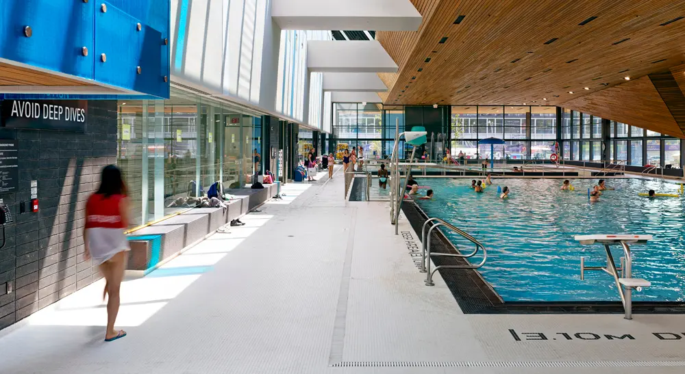 Inside the Regent Park Aquatic Centre: the indoor pool under a wood ceiling